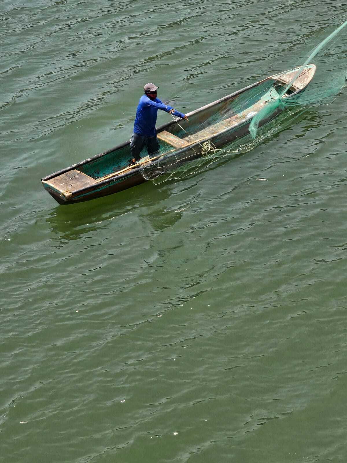 Pescador remando en canoa sobre la laguna.