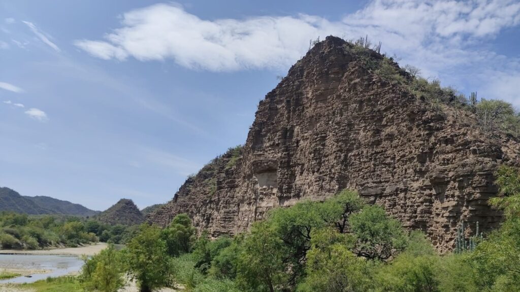 Cerro rocoso en forma de pico sobre la vegetación junto al río