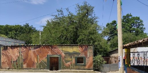 Casa de adobe con un mural de figuras humanas en tonos ocres
