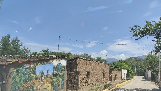 Calle con casas de adobe y un mural de paisaje en la fachada