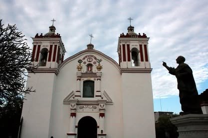 Templo blanco de dos torres junto a una escultura de bronce