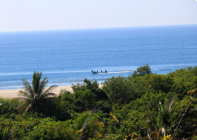 Barra de la Cruz Playa de Barra de la Cruz vista desde la vegetación costera, con lanchas fondeadas a lo lejos.