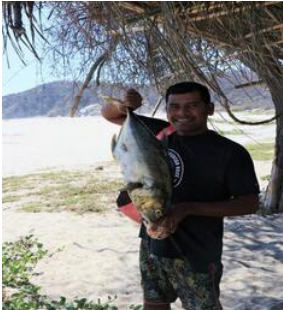 Fototeca Pescador de la comunidad sostiene un pez grande recién capturado en la playa.