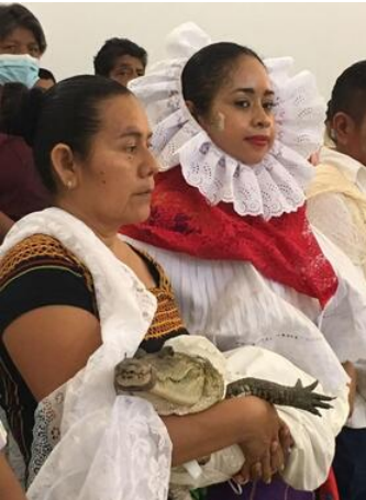 Fototeca Mujeres con traje regional durante la fiesta; una de ellas carga en brazos al caimán del ritual.