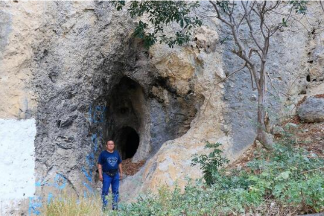 Fototeca Formación rocosa con una cueva; una persona de pie da escala al conjunto.