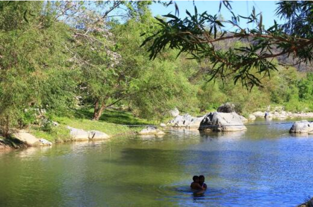 San Pedro Huamelula Poza de río rodeada de vegetación, con personas bañándose.