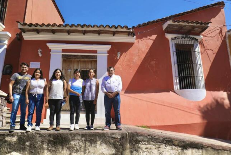 Fototeca Edificio colonial de muros rosados con un grupo de personas al frente.