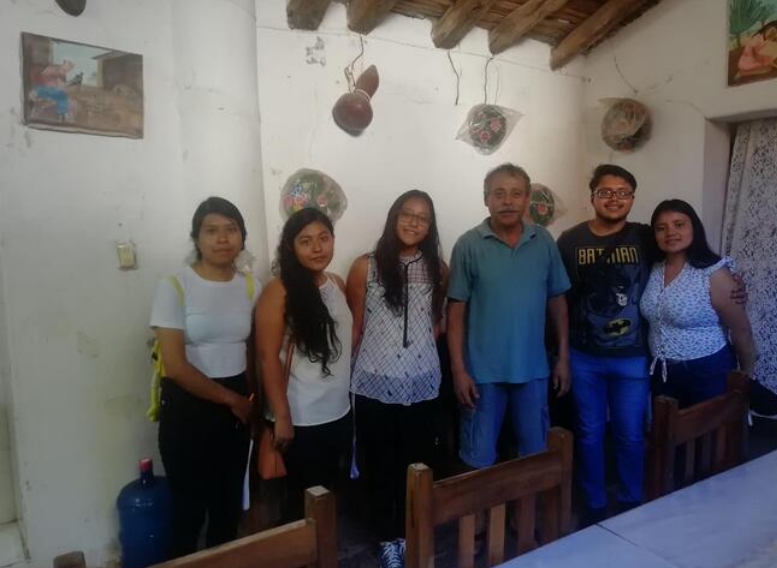 Fototeca Grupo de personas reunido en un interior con ollas de barro colgadas del muro.