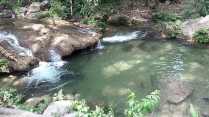 Poza de agua verde con pequeñas caídas de agua entre rocas