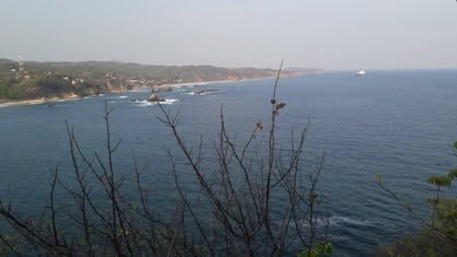 Mazunte y Punta Cometa: infraestructura turística de un Pueblo Mágico Bahía vista desde lo alto, con el mar en calma y vegetación seca en primer plano
