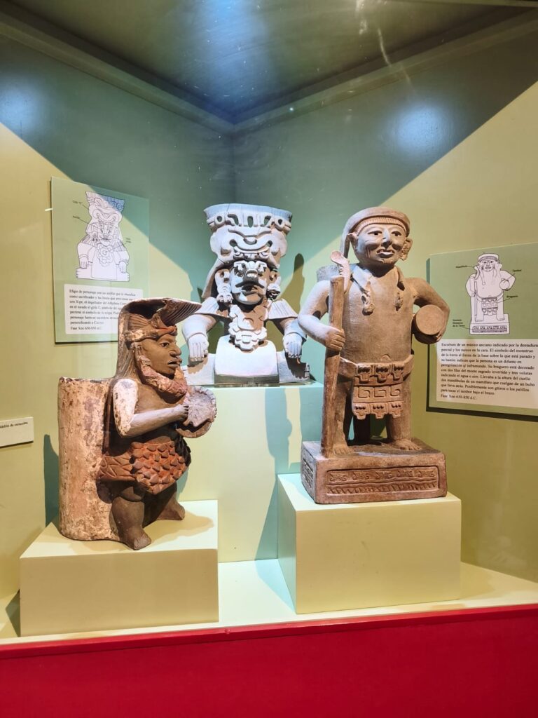 El Dr. Marcos Pedro Ramírez López, ponente en el conversatorio «El arte en Oaxaca a través del tiempo», en Mitla Vitrina con tres piezas zapotecas de cerámica: dos figuras de pie y una urna con tocado