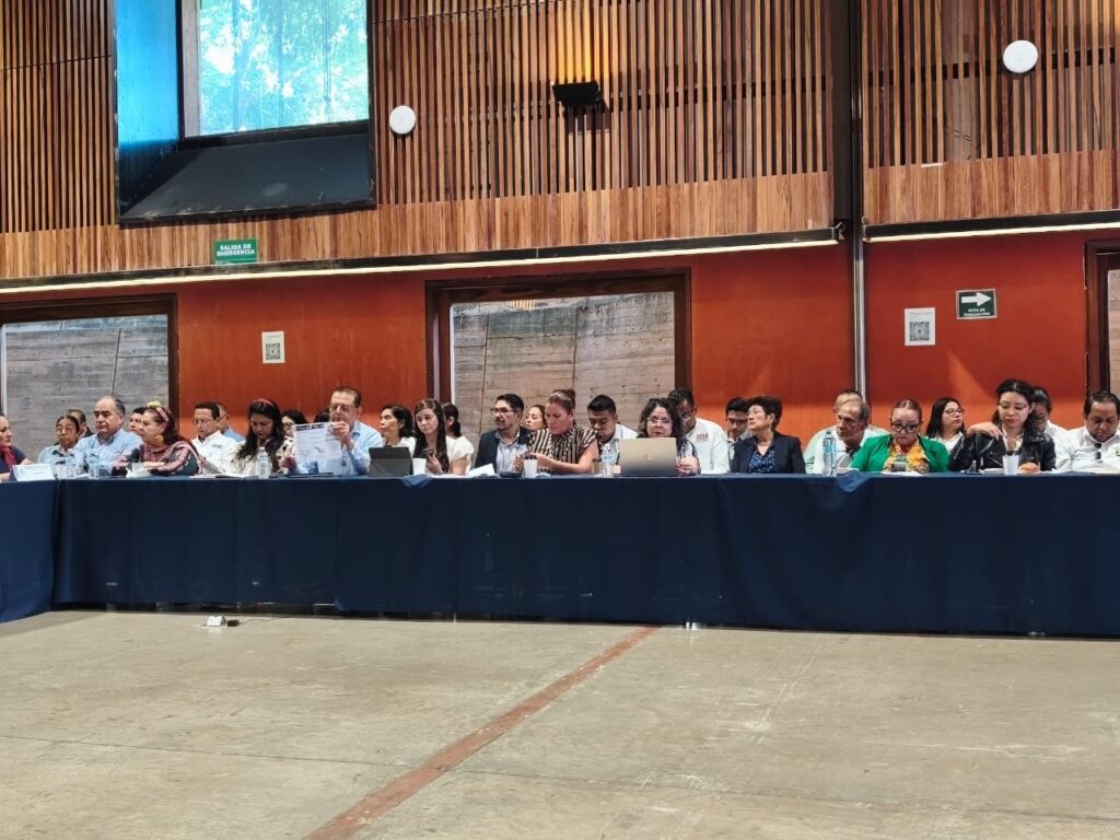 El grupo de turismo comunitario en NECTLI, la reunión regional Sur-Sureste del TecNM Participantes revisando documentos en una mesa larga de la sala de trabajo