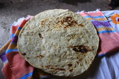 Tortilla grande de maíz sobre un mantel bordado de colores