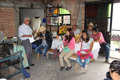Un señor de la comunidad conversa con un grupo de estudiantes sentadas en una sala