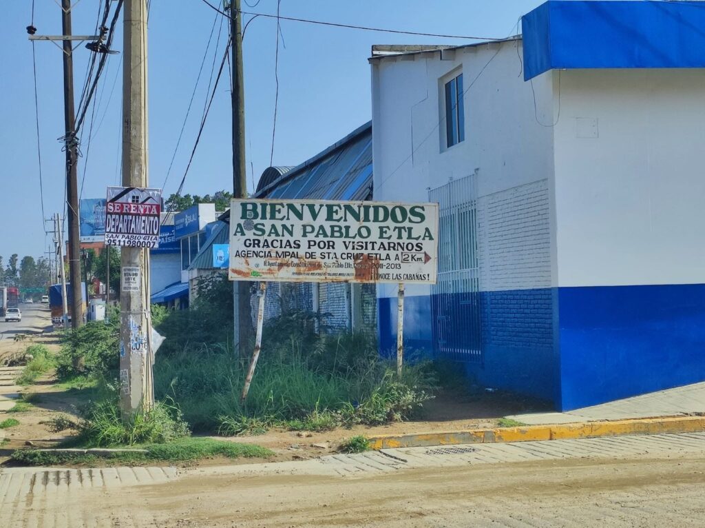 San Pablo Etla: acuerdos para fortalecer un proyecto ecoturístico Edificio pintado de blanco y azul con un letrero de bienvenida, junto a la carretera