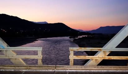Río visto desde un puente al anochecer, con cerros al fondo