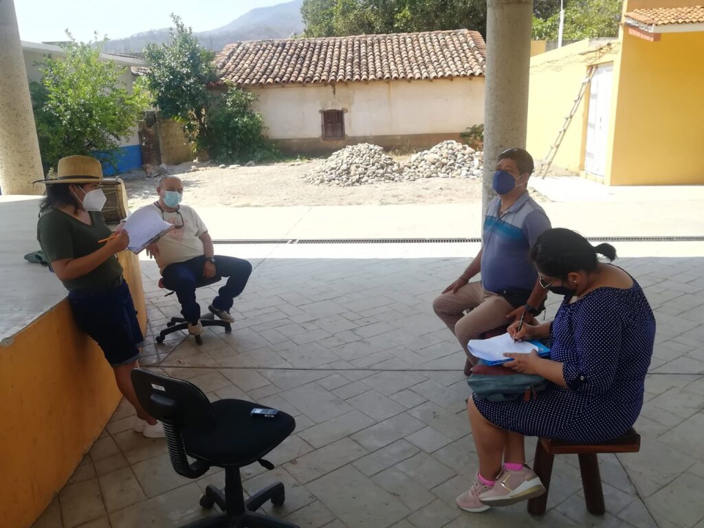 Varias personas sentadas conversan en el corredor de una casa