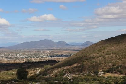 Memoria de campo 2011–2026 Valle amplio visto desde una ladera seca, con montañas al fondo